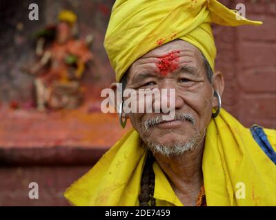 Älterer nepalesischer Hindu Gorakhnathi (Kanphata) Yogi Mönch mit großen Metallohrringen und roter Reiskleie auf der Stirn stellt sich für die Kamera. Stockfoto