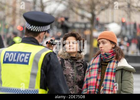 Weiße kaukasische Frauen Filmen einen Polizisten bei einem COVID 19 Coronavirus Anti-Lockdown-protestmarsch in London, Großbritannien. Mit Videokamera Stockfoto