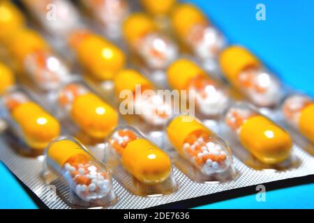 Kapseln in einer Blister, ein Medikament, Tabletten, Vitamine in Form von Granulat in einer gelben Kapsel, verschwimmen als kreative Technik des Autors, Nahaufnahme Stockfoto