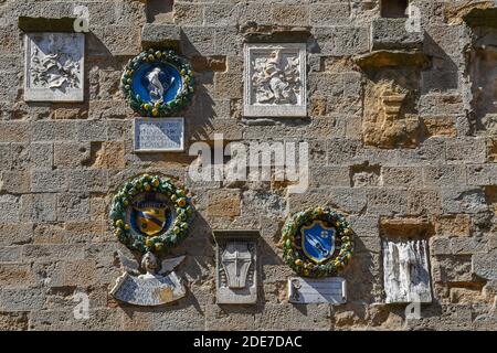 Emaillierte Terrakotta-Platten, die Wappen florentinischer Familien auf der façade des Palazzo dei Priori, Volterra, Toskana, Italien darstellen Stockfoto
