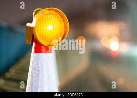 Verkehrskegel mit Licht auf der Oberseite bei Nacht England GB mit entfernten unscharf oder Bokeh Lichter der vorbeifahrenden Autos oder Verkehr, mit Kopierraum, Copyspace Stockfoto