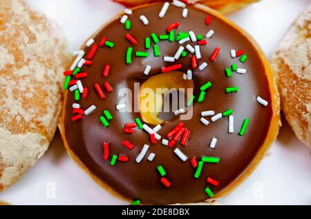 Ein Chocolate glazed Donut mit roten, weißen und grünen Streuseln ist Teil einer Holiday Box bei Krispy Kreme Donuts in Ocean Springs, Mississippi. Stockfoto