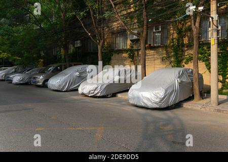 Viele überdachte Autos parkten auf einer Wohnstraße im zentralen Westen von Peking, China Stockfoto