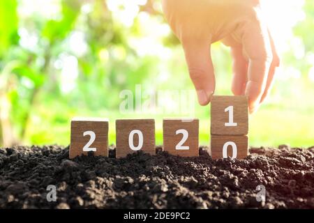 Männliche Hand begraben Jahr 2020 auf 2021 in Holzklötze Würfel ändern. Neujahr, Hallo und Auf Wiedersehen Konzept. Stockfoto