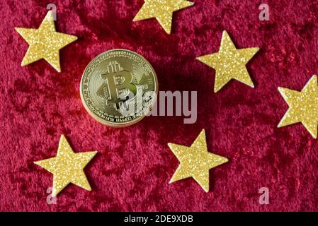 Stapel von Goldbitcoins auf einem roten Samthintergrund, mit goldenen Sternen Stockfoto