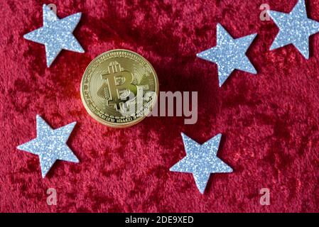 Stapel von Goldbitcoins auf einem roten Samthintergrund, mit silbernen Sternen Stockfoto
