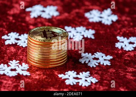 Stapel von Goldbitcoins auf einem roten Samthintergrund, mit weißen Schneeflocken Stockfoto