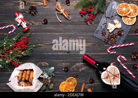 Flasche und Gläser Rotwein, Weihnachtsschmuck und Tannenzweige auf dunklem Holztisch. Vorlagenpapier für Notizen Stockfoto