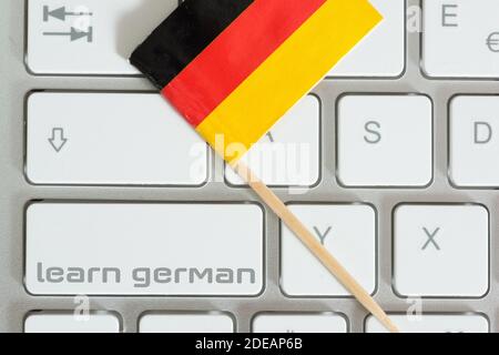 Ein Computer, eine Flagge Deutschlands und Deutsch lernen Stockfoto
