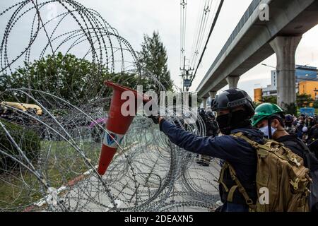 Bangkok, Thailand. November 2020. Ein Protestor entfernt am Sonntag, den 29. November 2020, bei einem prodemokratischen Protest vor dem 11. Infanterie RegimentÃs Hauptquartier in Bangkok, Thailand, Stacheldraht. Der Protestort war symbolisch, da das 11. Infanterie-Regiment traditionell als Leibwächter für die Könige von Thailand dient. Prodemokratische Demonstranten drängen weiterhin auf eine Regierungs- und Monarchie-Reform, wobei erstere in der Geschichte von ThailandÃs fast beispiellos ist. Quelle: Andre Malerba/ZUMA Wire/Alamy Live News Stockfoto