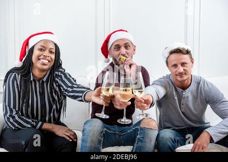 Eine Gruppe von Freunden, die zu Hause Weihnachten feiern und Champagner trinken Der Couch Stockfoto