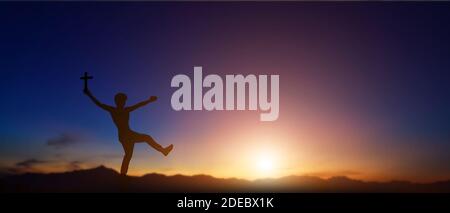 Silhouette des Mannes hält christian Kreuz in den Händen bei Sonnenuntergang Hintergrund. Stockfoto