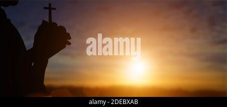 Silhouette von christian hält Kreuz in den Händen zu beten für Segen von gott bei Sonnenuntergang Hintergrund. Stockfoto
