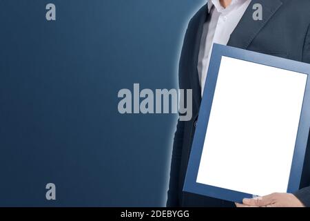 Mockup Geschäftsmann hält Diplom-Rahmen auf blauem Hintergrund. Mann hält leere Bild Zertifikat Abschlussrahmen. Mitarbeiter mit leerem Schild. Copyspa Stockfoto