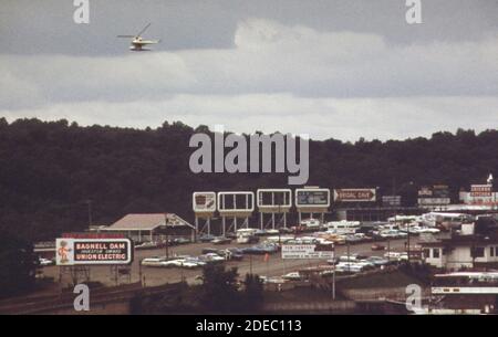 '1970er-Fotos (1973) - Bagnell Dam Ende des 'The Strip;'' ein kilometerlanges kommerzielles 'Funland', das sich entlang der Berggipfel südlich des Damms schlängelt. Diese Ansicht zeigt Casino Pier; Basis für Exkursionsboote; Sightseeing Float Flugzeug und Hubschrauber (Lake of the Ozarks Missouri Bereich) " Stockfoto