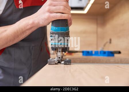 Reparaturman mit elektrischen Stichsäge. Sägeplatz für die Installation eines Gaskochfelds in einer Arbeitsplatte Stockfoto