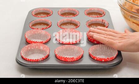 Muffin Pfanne mit Papier Cupcake Liner Nahaufnahme auf Küchentisch, Frau Hände. Stockfoto