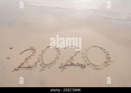 Meereswelle wischen weg 2020 Text Schrift auf weißem Sand Tropischer Strand am Morgen wunderschöner heller Sonnenaufgang am Strand Und Welle krachend auf sandigen Ufer Stockfoto