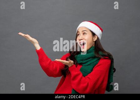 Studio Porträt einer fröhlichen asiatischen Frau trägt weihnachten Thema Kleidung mit aufgehobenen Armen, um den Raum zur Seite zu leeren Stockfoto