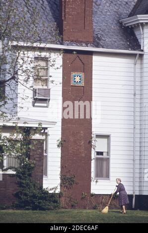 1970er-Fotos (1973) - Frau fegen ihren Rasen. Gegenüber von The First Christian Church in Columbus; indiana (Lage: Columbus; Indiana Gegend) Stockfoto