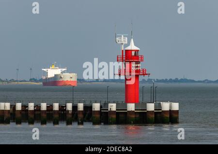 Roter Leuchtturm mit Frachtschiff im Hintergrund, Brunsbüttel, Schleswig-Holstein, Nordsee, Deutschland Stockfoto