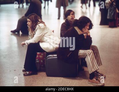 Koffer werden für Sitze verwendet, während Mitglieder der jüngeren Generation auf einen Zug in New York City's Penn Station (Pennsylvania Station) warten eine der belebtesten Zugrouten von New york ist, dass nach Washington D.C. Ca. 1973 Stockfoto