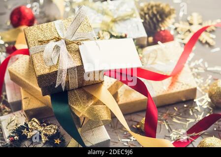 Stapel von glitzernden Silber und Gold Weihnachtsgeschenkboxen mit Bunte lockige Bänder und Dekorationsartikel auf dem Tisch Stockfoto