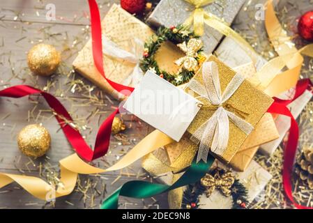 Stapel von glitzernden Silber und Gold Weihnachten Geschenkboxen mit bunten Bändern und Dekorationsartikel auf dem Tisch, Draufsicht Stockfoto