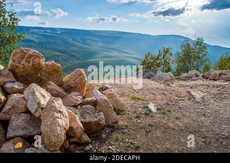 Haufen von Felsen und Steinen in der Nähe der Klippe bei Sonnenuntergang in Bergregion Stockfoto