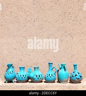 Traditionelle iranische Souvenirs - bunte Tonkrug und -Krug, Yazd, Iran. Tonkannen in verschiedenen Formen der blauen Farbe auf einem Regal in der Nähe der adobe-Wand. Kopieren Stockfoto