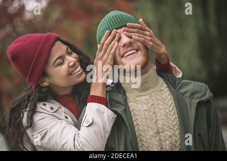 Frau, die die augen der menschen schließt, während sie im Park spazieren geht Stockfoto