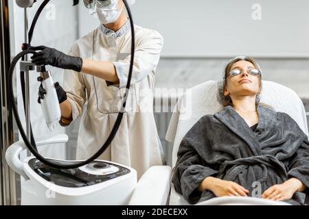 Junge Frau bereitet sich auf eine Verjüngungskur im medizinischen SPA vor Büro mit einem Arzt im Hintergrund Stockfoto