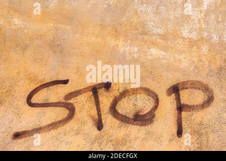 Das Wort Stop steht auf der orangefarbenen Vintage Wand Stockfoto