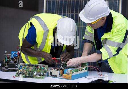 Ingenieur arbeiten Reparatur elektrische Panel mit Solarzellen Hintergrund, Konzept Teamarbeit oder Ausbildung von erneuerbaren. Stockfoto