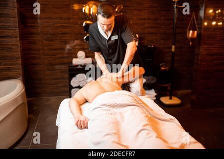 Professioneller Masseur, der eine Tiefenmassage für einen männlichen Klienten im Spa Salon macht, Schultermassage Stockfoto