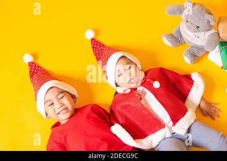 Asiatische kleine niedliche Kind Junge und Mädchen lächeln, Draufsicht auf zwei Brüder Kind in roten Weihnachtsmann hat das Konzept der Urlaub Weihnachten Weihnachtstag oder H gekleidet Stockfoto