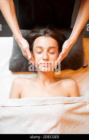 Junge Frau, die eine Gesichtsmassage erhält, sich im Spa-Salon entspannt, Blick von oben Stockfoto