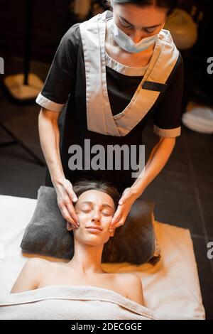 Junge Frau, die eine Gesichtsmassage erhält, sich im Spa-Salon entspannt Stockfoto