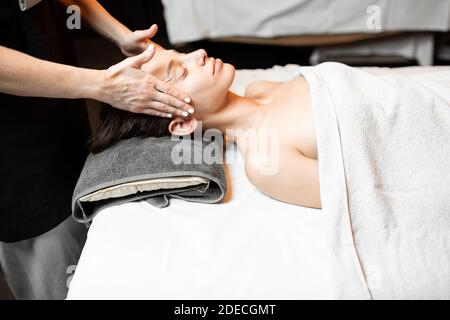 Junge Frau, die eine Gesichtsmassage erhält, sich im Spa-Salon entspannt Stockfoto