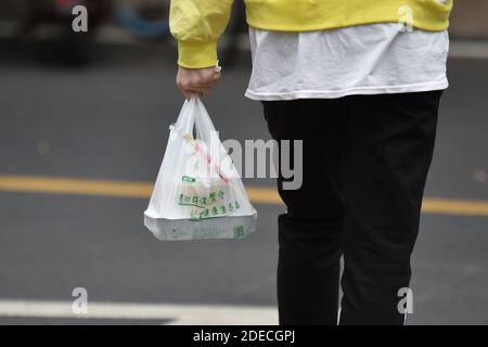 Haikou, China. November 2020. Ein Mann geht mit einer Plastiktüte, die in der Mensa der Hainan-Universität in Haikou verwendet wird.ab dem 1. Dezember wird das chinesische Unternehmen Hainan die Produktion, den Verkauf und die Verwendung einer breiten Palette von Einweg-Kunststoffprodukten verbieten, so die regionale Ökologie-Abteilung. Kredit: SOPA Images Limited/Alamy Live Nachrichten Stockfoto