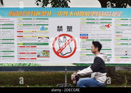 Haikou, China. November 2020. Ein Student der Universität fährt an einem Plakat vorbei, das Plastiktüten in Haikou verbietet.ab dem 1. Dezember wird Chinas Hainan die Herstellung, den Verkauf und die Verwendung einer breiten Palette von Einweg-Plastikprodukten verbieten, so die regionale Ökologie. Kredit: SOPA Images Limited/Alamy Live Nachrichten Stockfoto