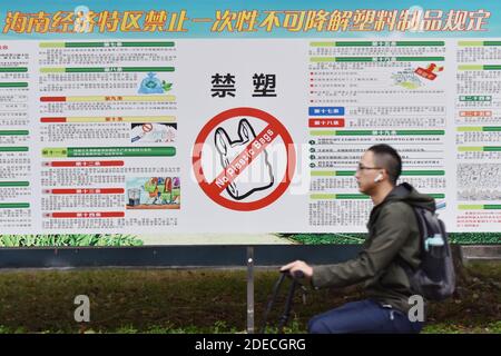 Haikou, China. November 2020. Ein Student der Universität fährt an einem Plakat vorbei, das Plastiktüten in Haikou verbietet.ab dem 1. Dezember wird Chinas Hainan die Herstellung, den Verkauf und die Verwendung einer breiten Palette von Einweg-Plastikprodukten verbieten, so die regionale Ökologie. Kredit: SOPA Images Limited/Alamy Live Nachrichten Stockfoto