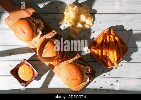 Nahaufnahme des hausgemachten Hamburgers mit Bier aus Rind, Zwiebeln, Tomaten, Salat, Käse und Gewürzen. Frische Burger auf rustikalem Holztisch Stockfoto