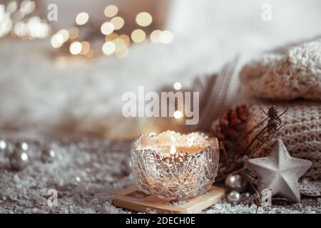 Schöne Weihnachtskerze in einem Kerzenständer auf einem hellen unscharfen Hintergrund. Das Konzept von Wohnkomfort und Wärme. Stockfoto