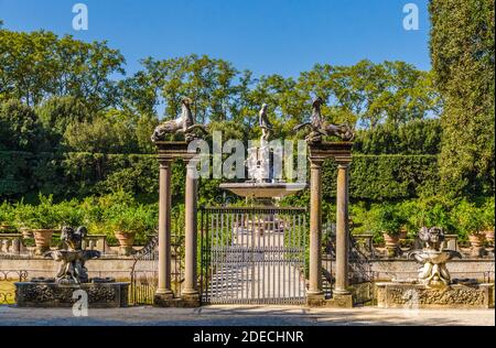 Blick auf den Eingang des Isolotto am Ende des Viottolone. Hinter dem eisernen Tor mit großen Säulen und Steinbock-Statuen auf der Oberseite, und Triton... Stockfoto