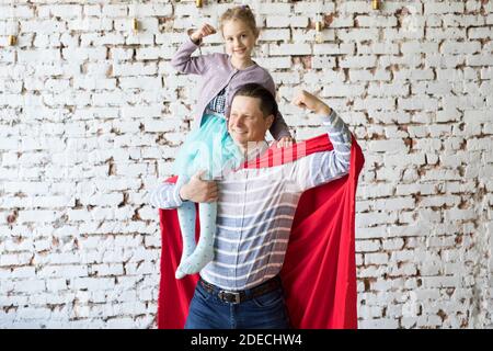 Glücklicher Vater in Superhelden-Kostüm und seine Tochter Stockfoto