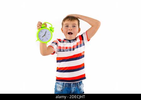 Schockiert niedlichen Jungen halten Wecker auf weiß isoliert Studio Hintergrund. Stockfoto