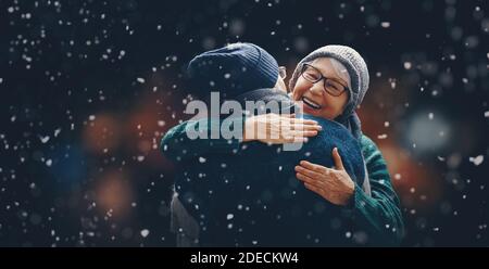 Frohe Weihnachten! Winterportrait des älteren Paares auf schneebedecktem dunklen Hintergrund. Stockfoto