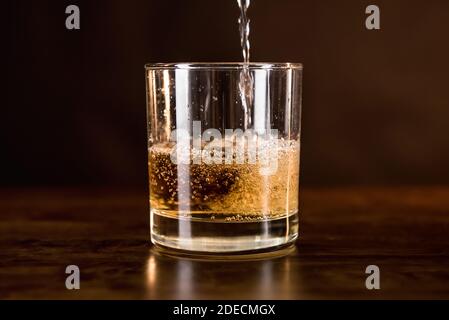Whisky-Getränk wird in das Glas auf Holz gegossen Theke Bar - Konzept für Spirituosen und alkoholische Getränke Stockfoto