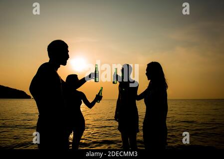 Gruppe von jungen Freunden trinken und Party im Urlaub Bei warmem Klima Strand am Abend Sonnenuntergang Stockfoto